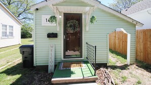 Una casa pequeña de un solo piso, con puerta verde, felpudo y letrero con el número 14.