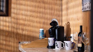 Un comptoir de cuisine avec une machine à café, des tasses à café, une bouteille de vin et des verres.