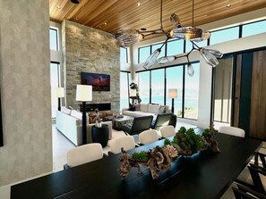 A modern dining area with a long table, chairs, and a decorative centerpiece.