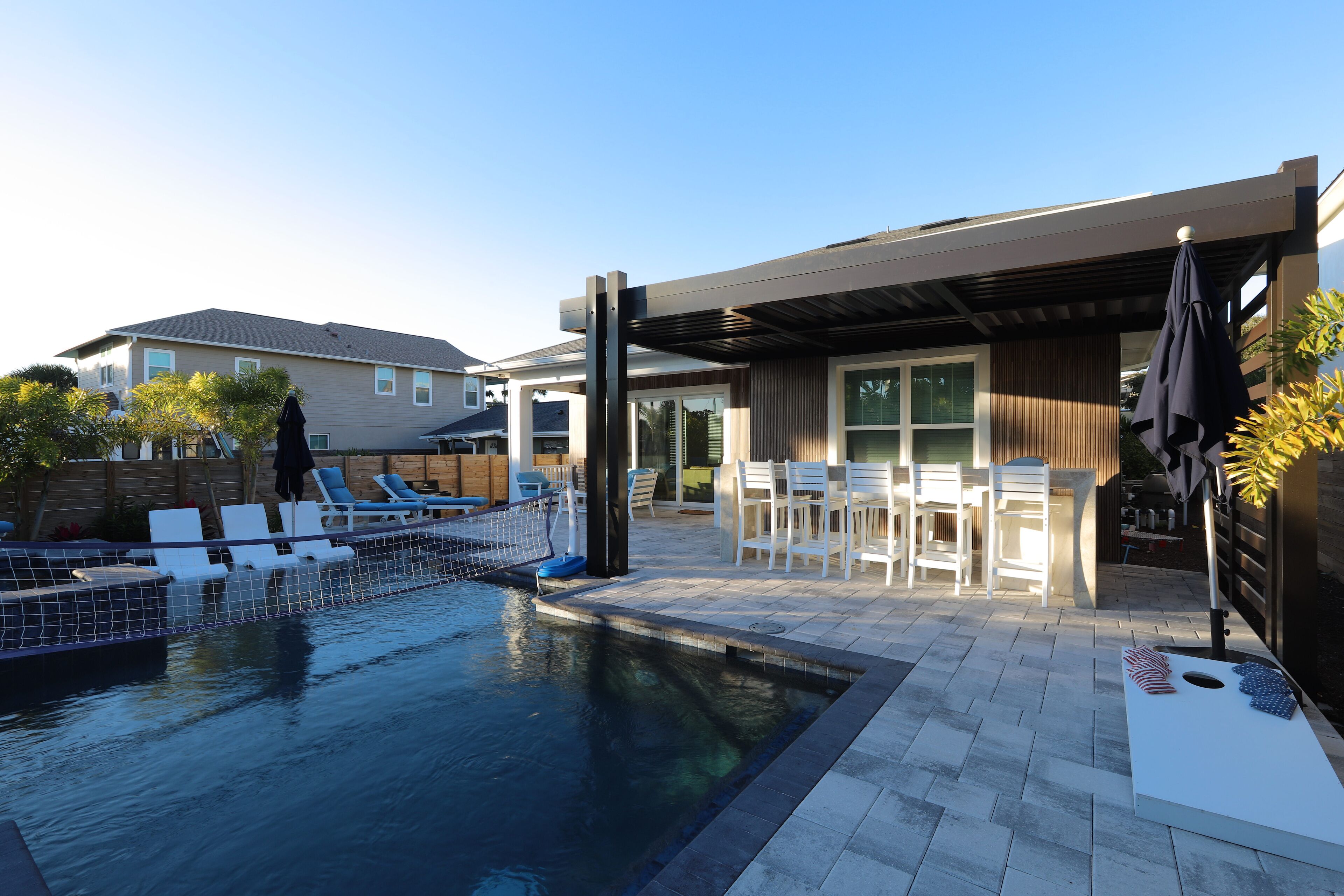 Un espace piscine extérieur moderne comprenant des chaises longues, une petite piscine et une terrasse avec des chaises et des tables.