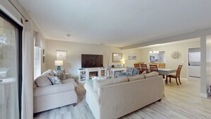 Una sala de estar moderna con un sofá, una televisión, una chimenea y un comedor con mesa y sillas.