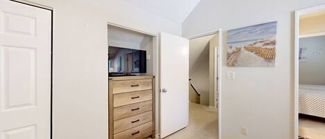 Un dormitorio con cama, cómoda, televisor y un cuadro en la pared.