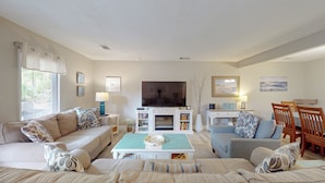 Una sala de estar con chimenea, sofá, televisor y comedor.