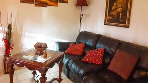 Un saló amb un sofà de cuir negre, una taula de centre de fusta i un quadre a la paret.