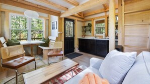 A cozy cabin interior with a dining area, kitchen, and seating space. - TreeTops, modern luxury overlooking Keuka Lake - Luxury Treehouse included (Penn Yan)