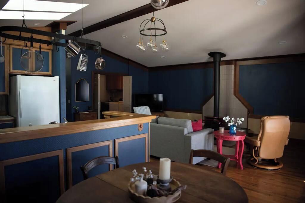 Eine moderne Küche mit Holztisch, einem Esstisch mit Kerzenarrangements und einer gemütlichen Wohnbereits mit Sofa und Fernseher.