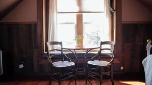 A cozy room with a wooden floor, a window with curtains, and two wicker chairs. - Plaza Perch~Downtown~Walkable (Arcata)