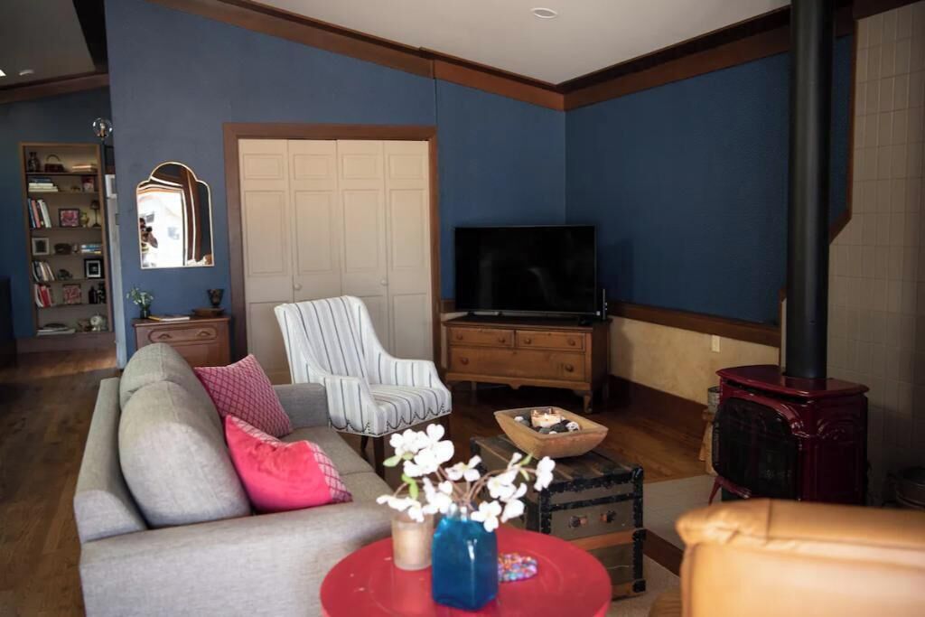 Una sala de estar con sofá, sillón, televisión y chimenea.