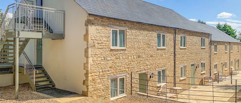 A stone building with a staircase, multiple windows, and a covered outdoor area.