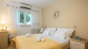 A hotel room with a bed, a bedside table, a chair, a desk, and a window with curtains. - Lavica seaside apartments (Podstrana)