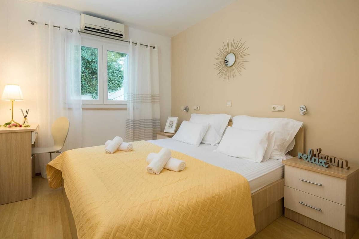 Ein Hotelzimmer mit Bett, Nachttisch, Stuhl, Schreibtisch und einem Fenster mit Vorhängen.