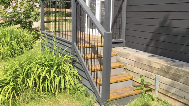 A dark wooden house with a grey metal staircase and a white door.