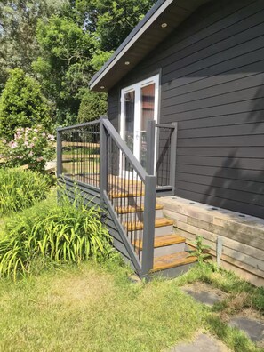 A dark wooden house with a grey metal staircase and a white door. - Cosy cabin in the beautiful West side of the Isle of Wight. Pet Friendly! (Freshwater)