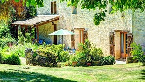 A stone building with a covered patio, a small table, and potted plants. - Beautiful Stone Farmhouse, Private Pool, Idyllic Setting Amongst Vineyards near Sainte-Foy-la-Grande (Sainte Foy la Grande)