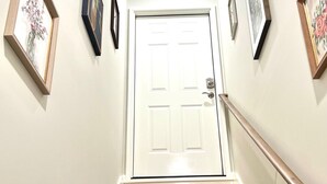 Una escalera con escalones de madera que lleva a una puerta blanca con picaporte y cerradura.