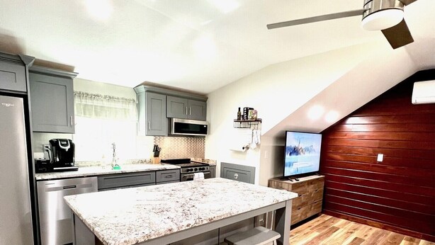 Una cocina moderna con una isla central, suelo de madera y un ventilador de techo.