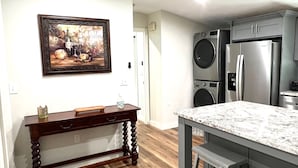 Una cocina con una mesa de madera, encimera de mármol, refrigerador de acero inoxidable y lavadora empotrada.