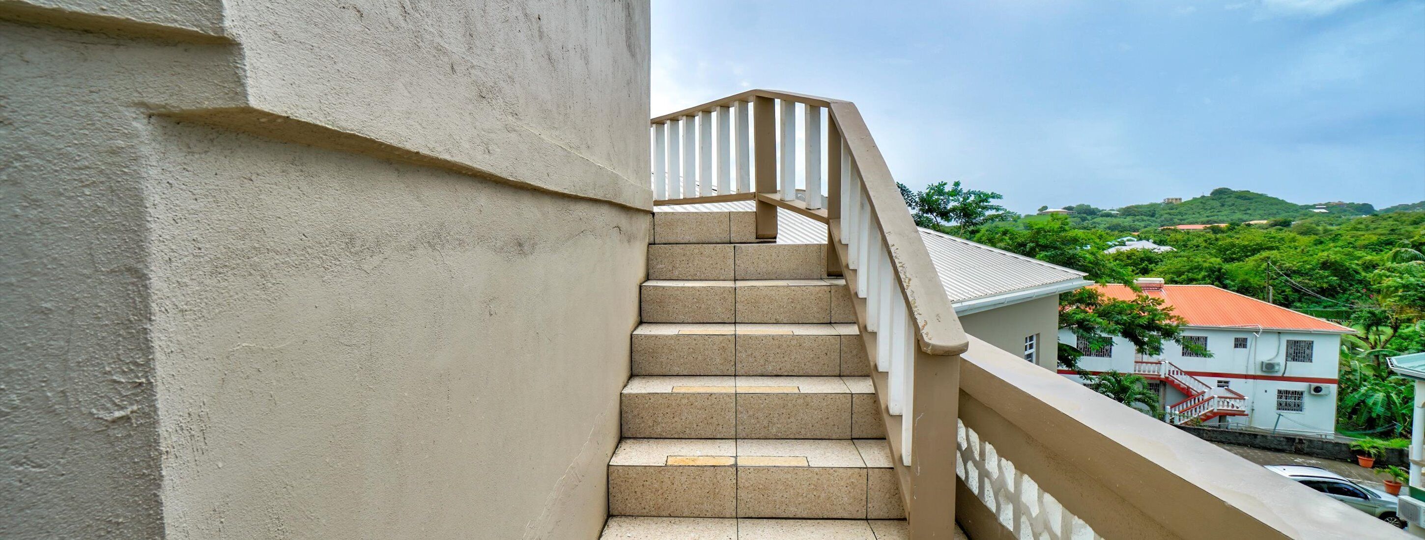 Una escalera de concreto con barandillas blancas que sube a un nivel superior.