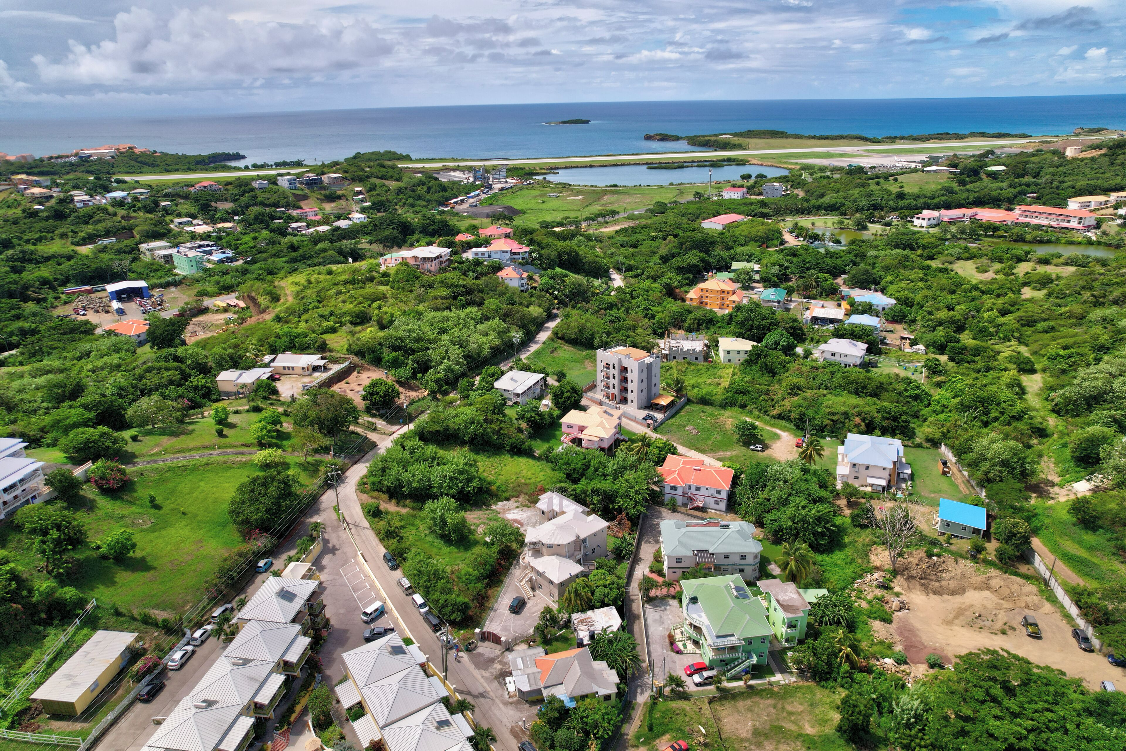 Vista aérea de uma área residencial costeira com casas, ruas e uma praia.