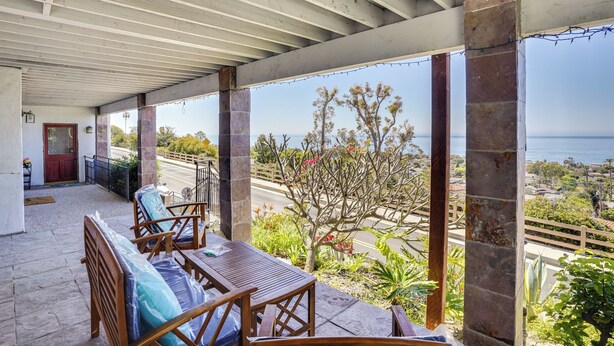 Eine überdachte Terrasse mit Holzmöbeln und Blick auf das Meer.