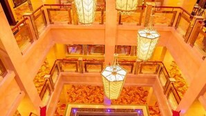 Un atrium à plusieurs niveaux, doté d’un élément aquatique central, de nombreux étages et de luminaires suspendus de style lanterne.