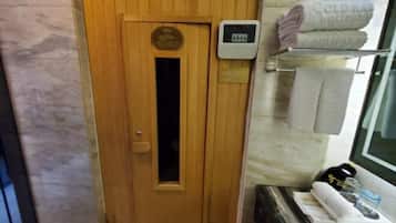 Une porte en bois menant au sauna, ornée d’une plaque, un panneau de commande, des serviettes et une petite table avec une bouteille et un verre.