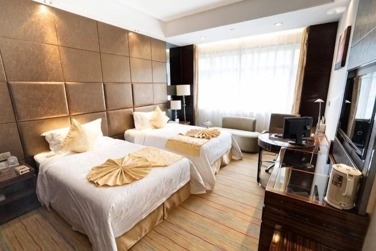 Une chambre d’hôtel avec deux lits, un bureau, une télévision et une grande fenêtre.