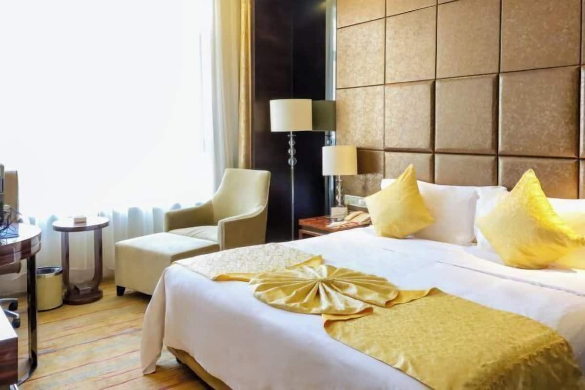 Une chambre d’hôtel avec un grand lit, une chaise, un bureau et une lampe.