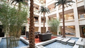 Un hall d’hôtel doté d’un espace salon central, de plusieurs étages et de plantes d’intérieur.