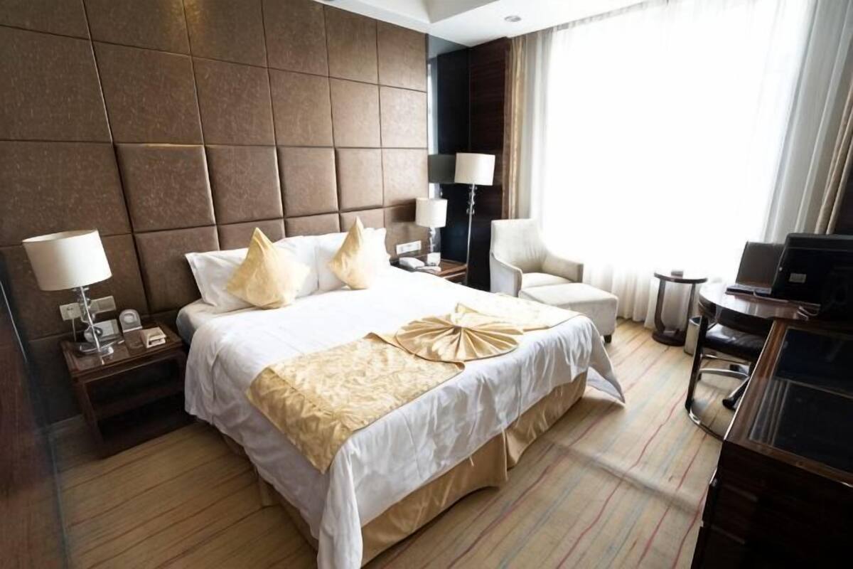 Une chambre d’hôtel avec un grand lit, des lampes de chevet, un bureau avec un ordinateur portable et une chaise.