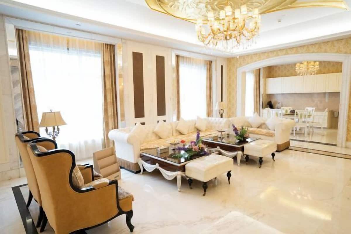 Un salon luxueux comprenant un ensemble de canapés, des fauteuils, une table basse et un lustre.