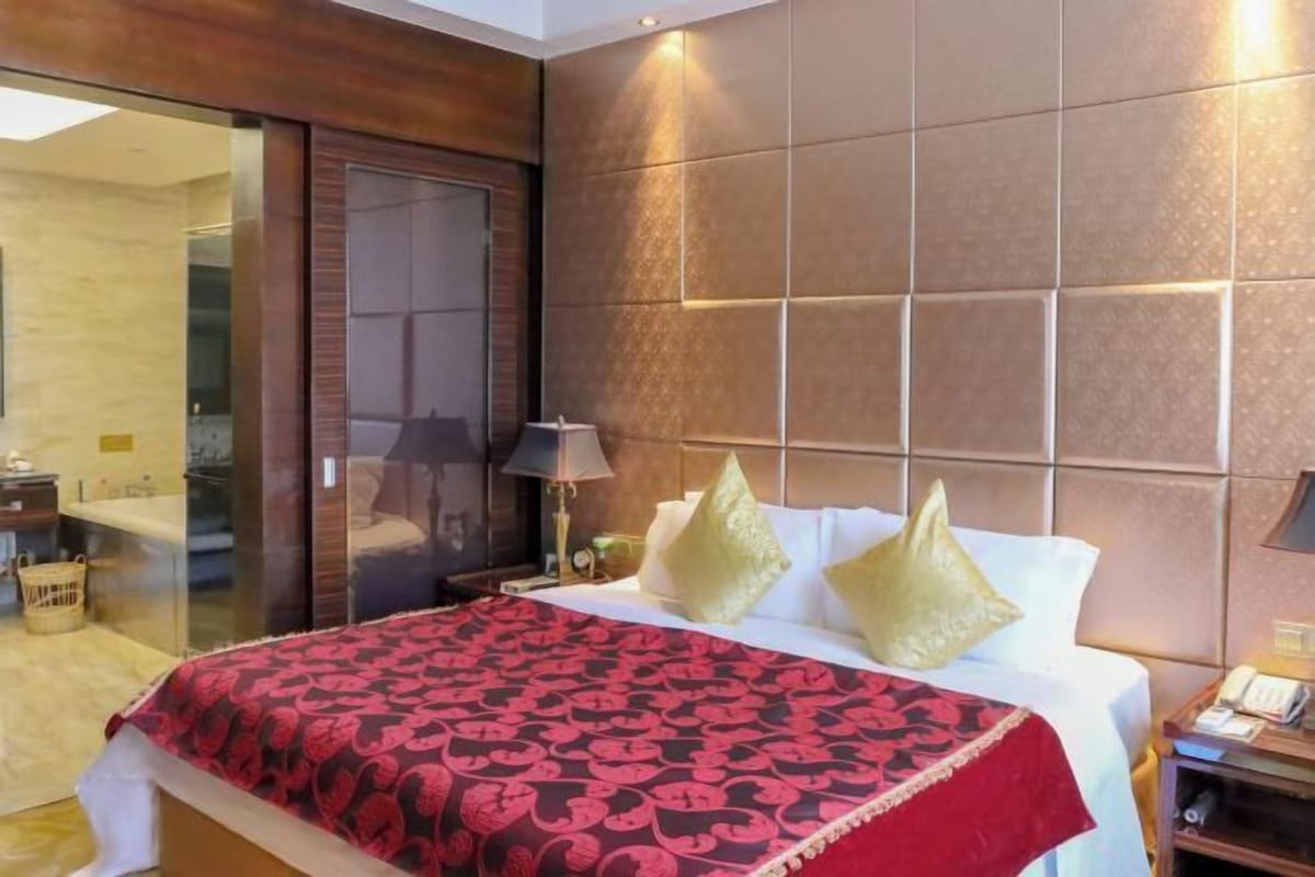 A hotel room with a bed, a nightstand, a lamp, and a sliding door to a bathroom.