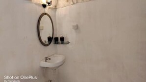 Une salle de bain avec un lavabo blanc, un miroir et une étagère contenant des articles de toilette.