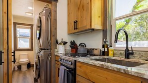 A compact kitchen with wooden cabinets, a stainless steel refrigerator, a built-in oven, a gas stove, and a sink. - Beautiful NEW 1-bed, 1-bath right in downtown Cody! Sleeps up to 4.  (Cody)
