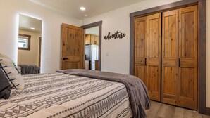 A bedroom with a bed, a wooden wardrobe, and a wall with the word "adventure". - Beautiful NEW 1-bed, 1-bath right in downtown Cody! Sleeps up to 4.  (Cody)