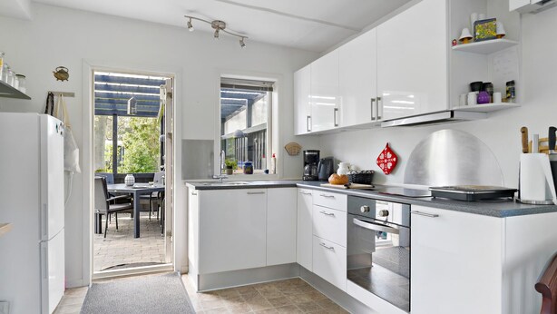 A modern kitchen with white cabinets, a built-in oven, and a coffee maker.