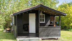 A small wooden cabin with a porch, a door, and a window.