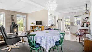 A modern dining area with a round table, green chairs, a fireplace, and a television.