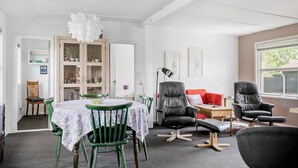 A room with a dining table, chairs, a sofa, and a window.