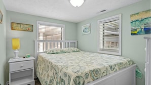 A bedroom with a bed, a nightstand, a lamp, and a window with blinds. - 1802A Ocean Lakes Pet Friendly Golf Cart⛱️🏝️🩱🌊👙☀️🐚 (Myrtle Beach)