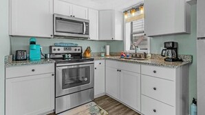 A compact kitchen with white cabinets, a stainless steel oven, a microwave, and a coffee maker. - 1802A Ocean Lakes Pet Friendly Golf Cart⛱️🏝️🩱🌊👙☀️🐚 (Myrtle Beach)