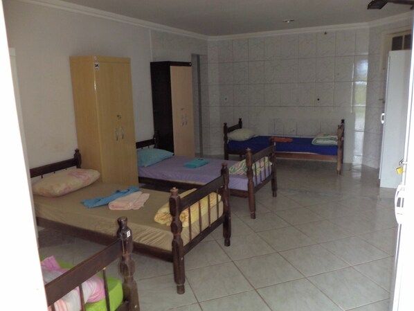 A room with two single beds, a wardrobe, and a tiled floor.