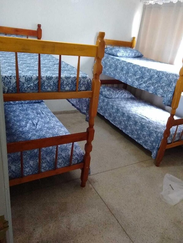 Una habitación con tres literas de madera, cada una con un colchón azul y blanco estampado.