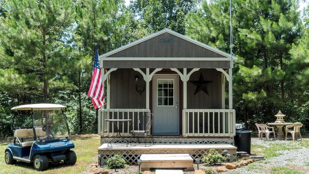 A small cabin with a porch, a golf cart, and outdoor seating. - Meadows - A tiny touch of heaven at Stag Leap Cabins! (Nacogdoches)