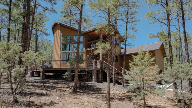 A cabin with a wooden exterior, large windows, and a balcony. - OASIS IN THE FOREST ON 1.25 ACRE BACKING TO NATIONAL FOREST WITH AC-PETS WELCOME (Show Low)