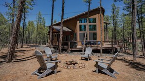 A cabin with a deck, surrounded by trees, and featuring two Adirondack chairs and a fire pit. - OASIS IN THE FOREST ON 1.25 ACRE BACKING TO NATIONAL FOREST WITH AC-PETS WELCOME (Show Low)