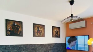 Un salón moderno con un sofá gris, una pared de acento de piedra y tres obras de arte enmarcadas.