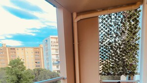 Un balcón con una mesa redonda y cuatro sillas, con vistas a una zona residencial con edificios y árboles.