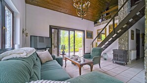 A spacious living room with a green sofa, a television, and a staircase leading to an upper level. - Beautiful home in Donji Zvecaj with WiFi (Donji Zvecaj)