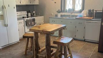 A kitchen with white cabinets, a wooden table, and stools.